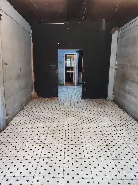 Shophouse for rent or sale in Khlong Toei, Bangkok - Long narrow shophouse room with white-and-black tiled floor, raw concrete walls and a doorway to the back area.