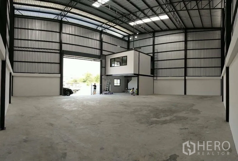 Warehouse for rent in Bang Phli, Samut Prakan - Spacious warehouse interior with high steel truss roof and mezzanine office box.