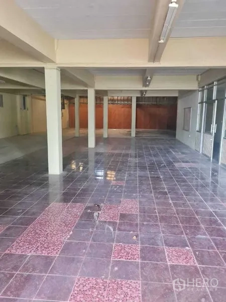 Warehouse for rent in Bang Yai, Nonthaburi - Open-plan hall with columns, glossy maroon tiles and fluorescent lighting.