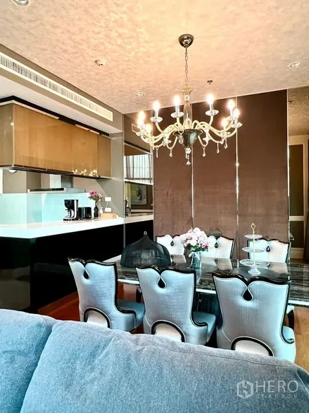 Condominium for rent in Khlong Toei, Bangkok - Dining space beside the kitchen island under an ornate chandelier.
