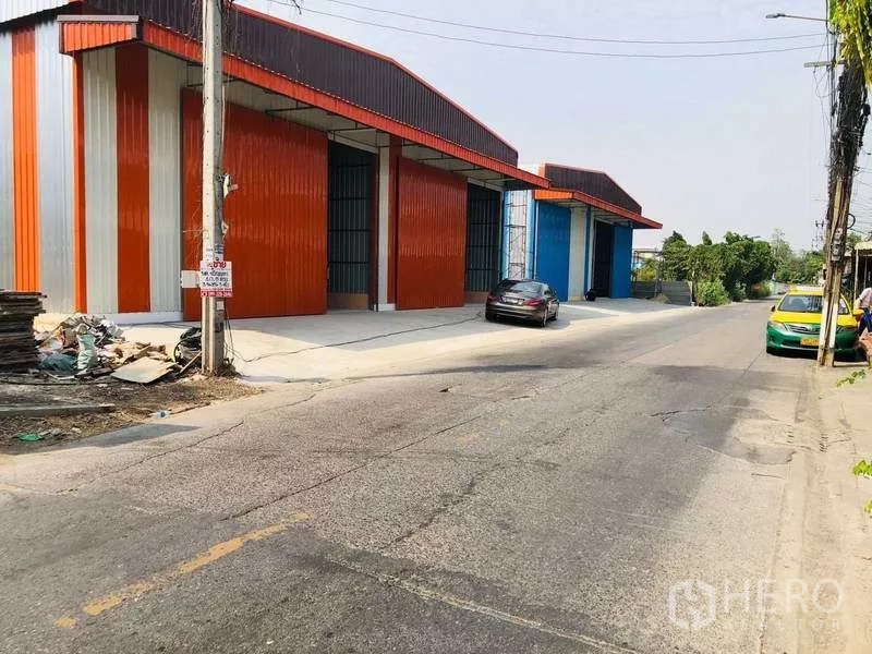 Warehouse for rent in Bueng Kum, Bangkok - Roadside view of multiple warehouse bays with tall metal doors and truck-friendly access.