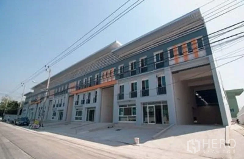 Factory for rent in Bang Sao Thong, Samut Prakan - Row of modern factory units with wide drive-in bays along a clean industrial street.