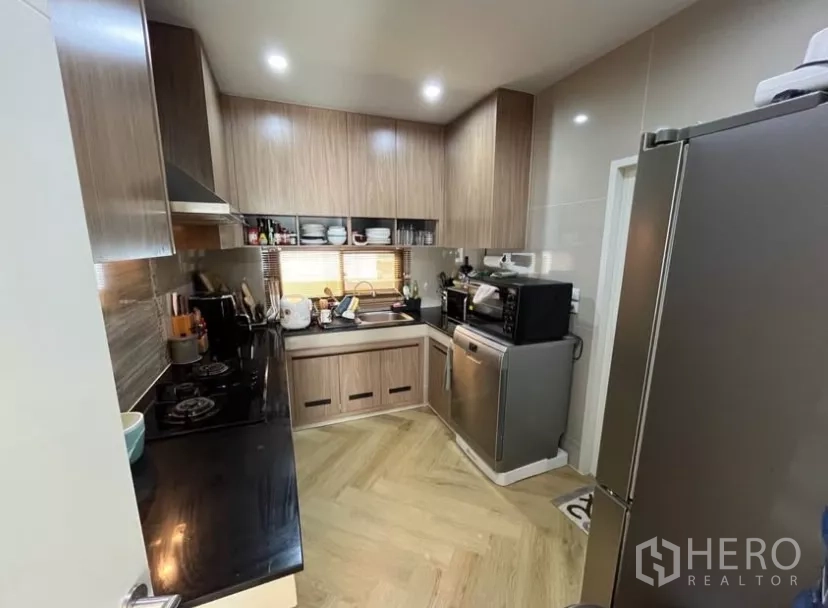 Detached House for rent in Prawet, Bangkok - Compact L-shaped kitchen with wood cabinetry, stone counters and full appliances.