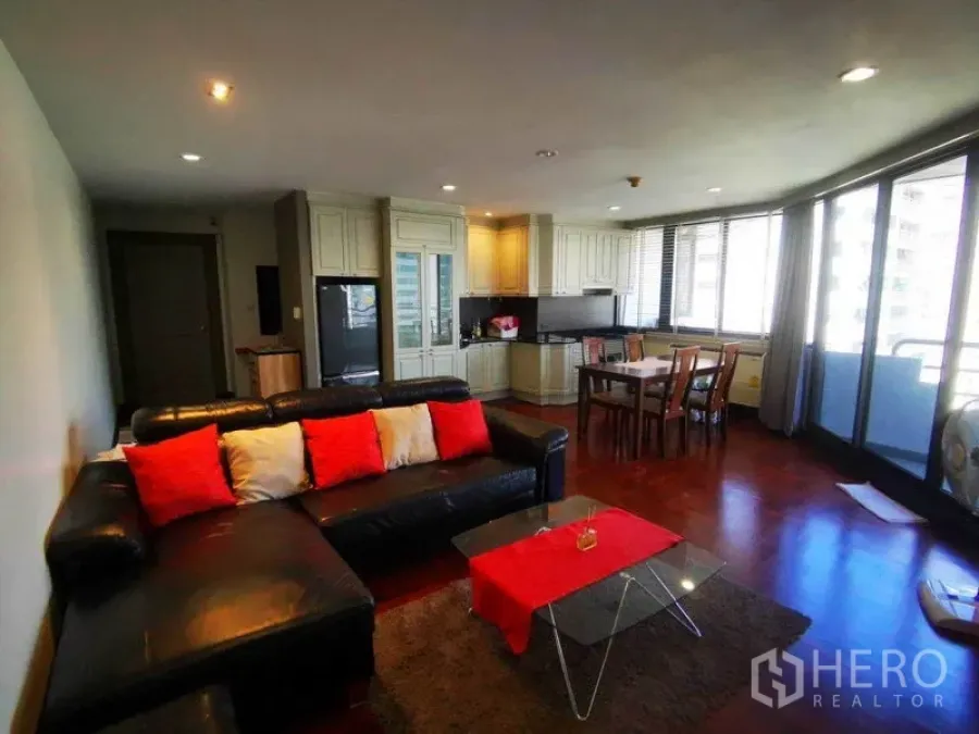 Condominium for rent in Khlong Toei, Bangkok - Open-plan living area with kitchen and dining, large glass doors leading to the balcony.