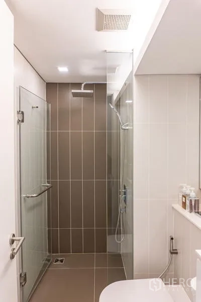 Condominium for rent in Khlong Toei, Bangkok - Walk‑in shower with rain head and clear glass door in a tiled bathroom.