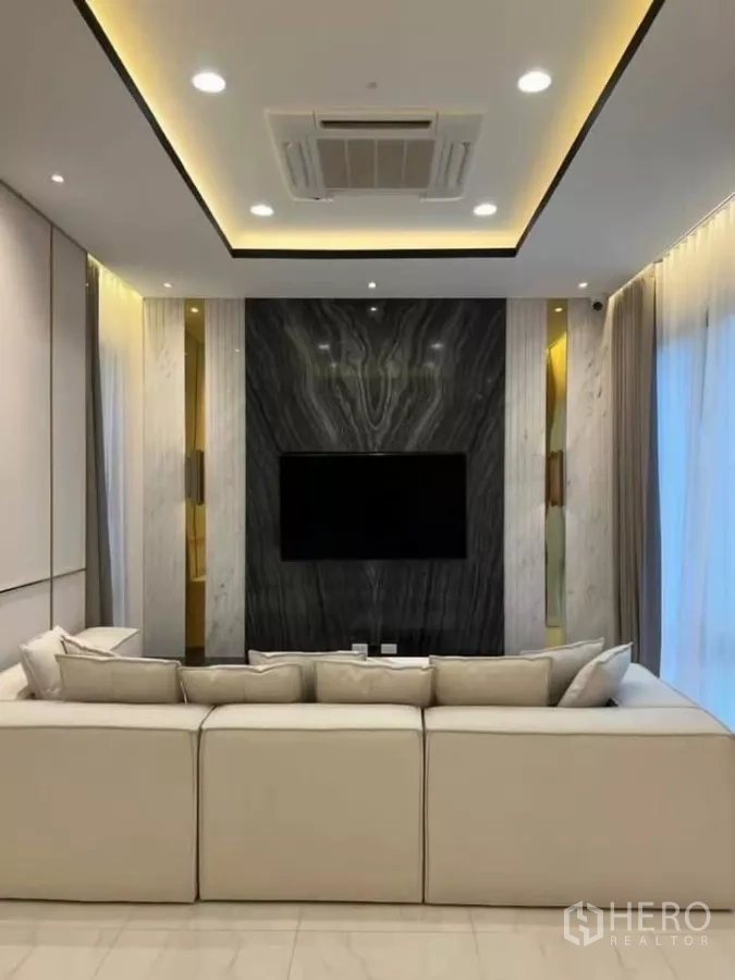 Detached House for rent in Phaya Thai, Bangkok - TV feature wall with dark marble slab, warm lighting and cream sofa seating.