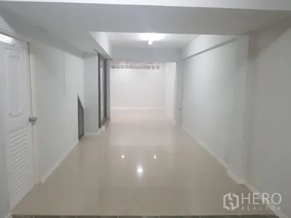Shophouse for rent or sale in Lat Phrao, Bangkok - Bright open-plan ground floor with glossy tiled floors and white walls.