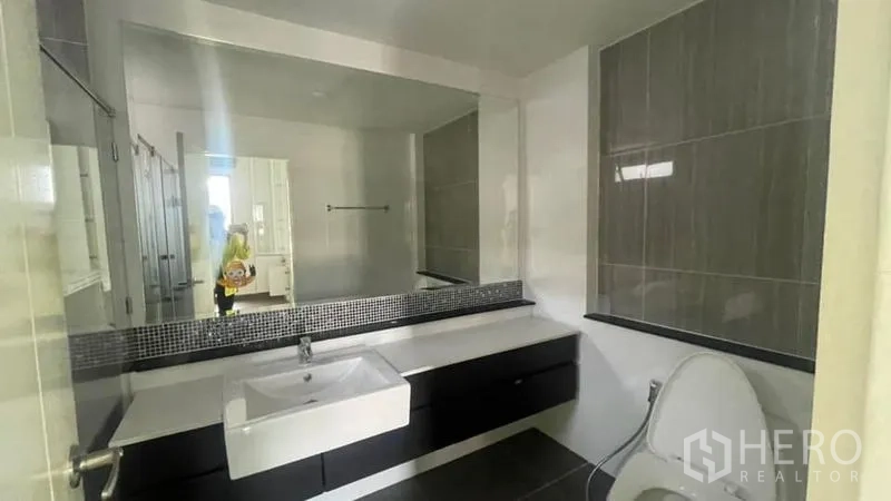 Detached House for rent or sale in Prawet, Bangkok - Modern bathroom with long vanity, square basin and large mirror.