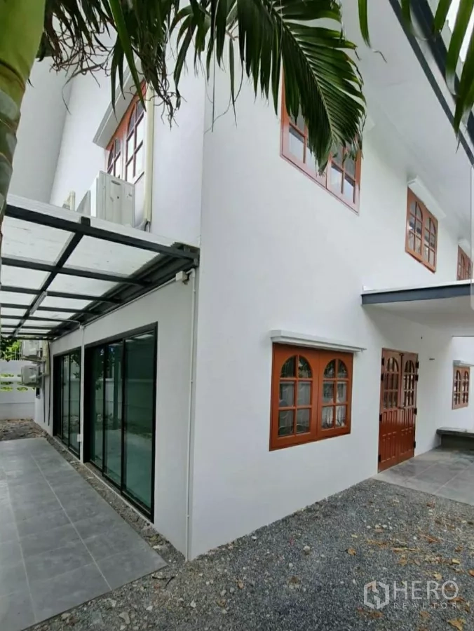 Home Office for rent in Lat Phrao, Bangkok - Side elevation with covered walkway, large sliding glass doors and wood‑trim windows.