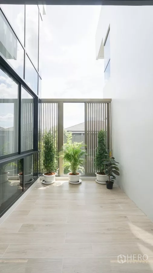 Detached House for rent or sale in Bang Kapi, Bangkok - Covered balcony with potted plants and light wood-look tiles.