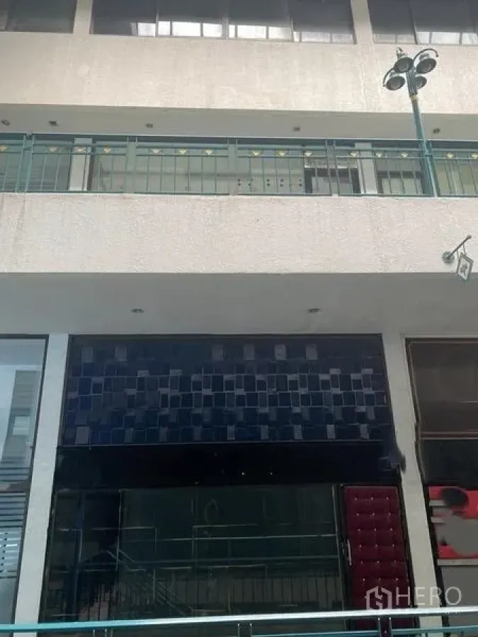 Shophouse for rent in Huai Khwang, Bangkok - Shophouse exterior in a commercial arcade with balcony railings and a wide glass frontage.