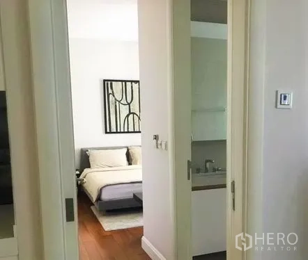 Condominium for rent in Pathum Wan, Bangkok - Hallway with sliding doors leading to a bedroom and a bathroom vanity.