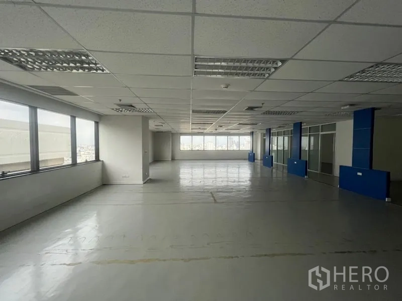 Office Space for rent - Open‑plan office floor with grid ceiling lights and long windows offering city views.