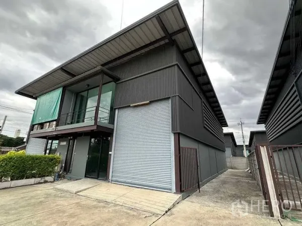 Warehouse for rent in Bang Phli, Samut Prakan - Angle view of the warehouse block with wide driveway, gated side access, and corrugated panels.