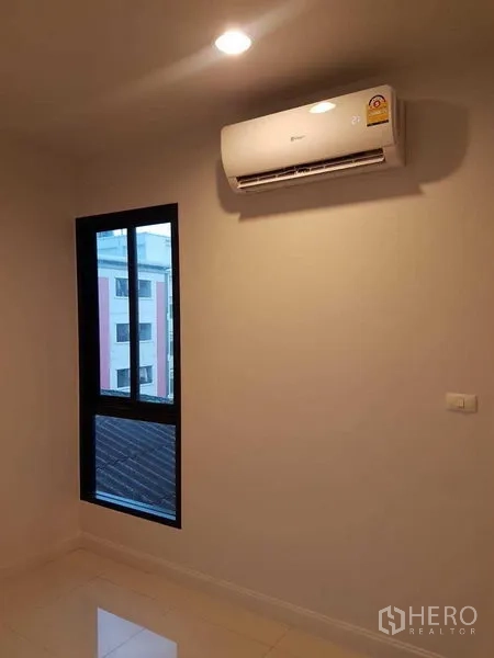 Shophouse for rent or sale in Bang Na, Bangkok - Bedroom corner with window and wall-mounted air conditioner.