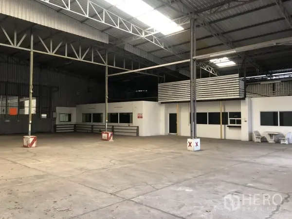 Warehouse for rent in Pak Kret, Nonthaburi - Spacious warehouse interior with high steel truss roof, skylights, and built-in office rooms.