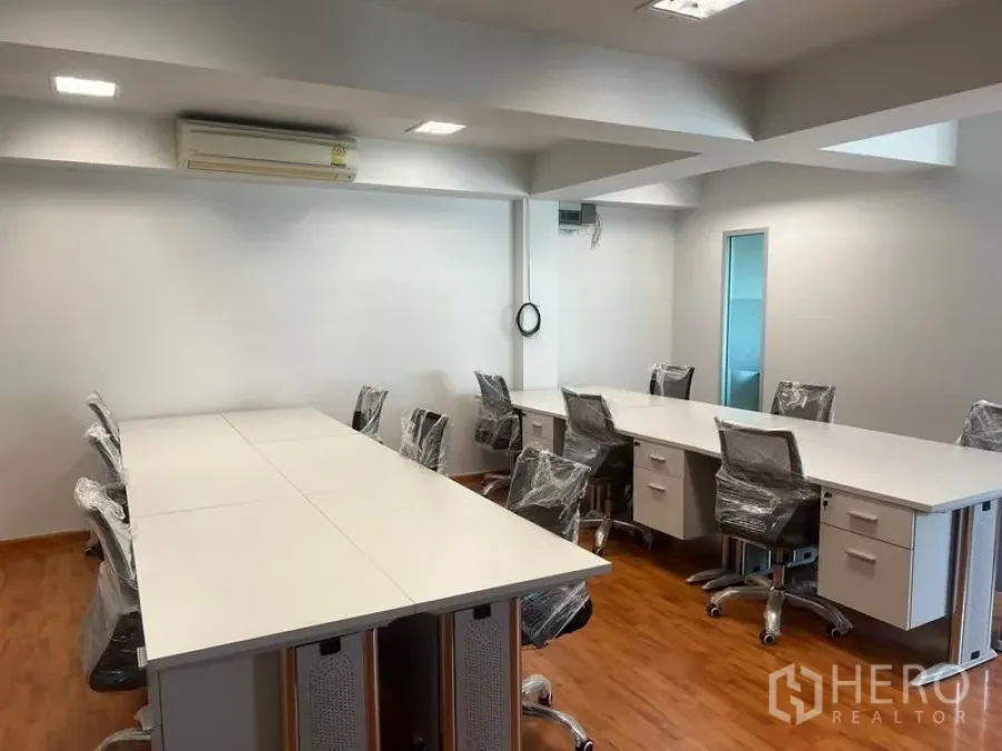 办公空间 出租在Khlong Toei, Bangkok - 开放式办公室，白色长桌、带轮椅、木地板与嵌入式灯光。