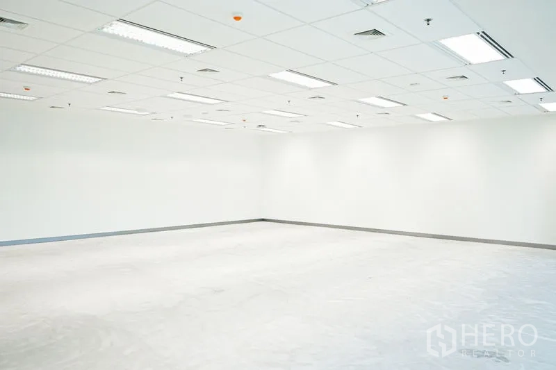 Office Space for rent in Bang Na, Bangkok - Empty office corner with white walls, ceiling vents and fluorescent lighting, ready for customization.