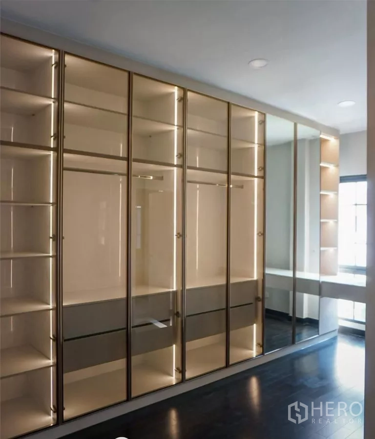 Detached House for rent or sale in Bang Phli, Samut Prakan - Walk-in closet featuring glass-front wardrobes with display lighting and a full-height mirror.