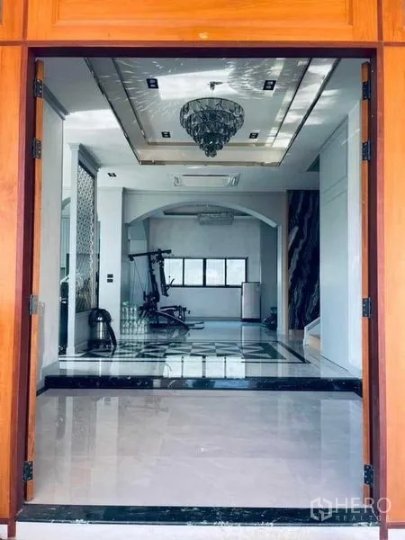 Detached House for sale in Mueang Nonthaburi, Nonthaburi - Formal entry hall with glossy floors, chandelier and fitness area visible beyond an archway.