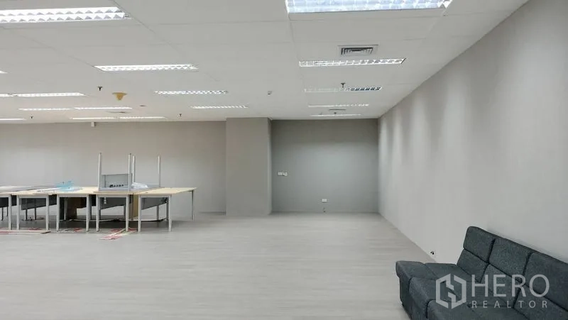 办公空间 出租或出售在Pathum Wan, Bangkok - 宽敞开放式办公区，灰色墙面、沙发与工位，LED照明。
