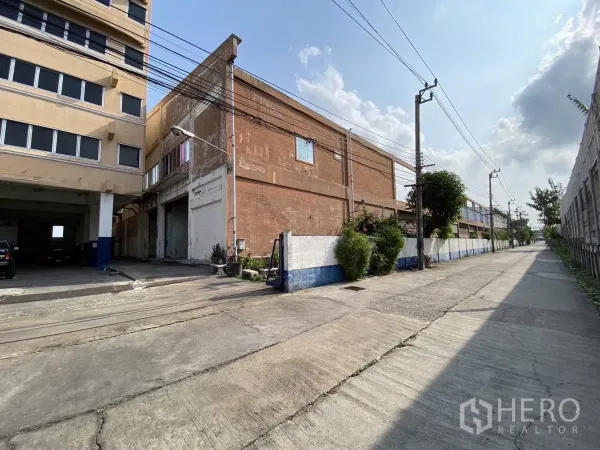工厂 出售在Bang Phli, Samut Prakan - 入口车道紧邻红砖厂房与宽阔道路。