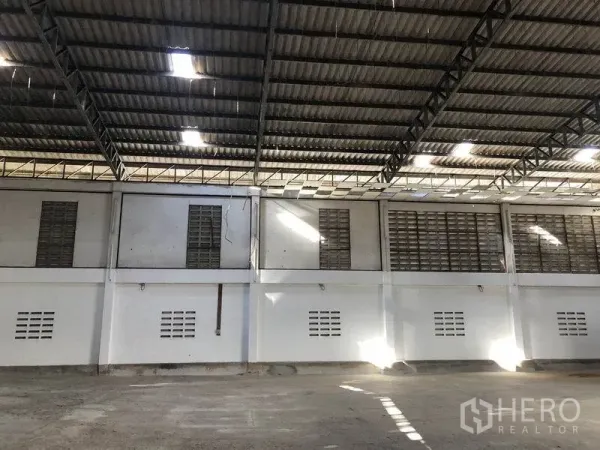 Warehouse for rent in Khlong Sam Wa, Bangkok - Side wall of the warehouse with steel roof trusses and skylights providing natural light.