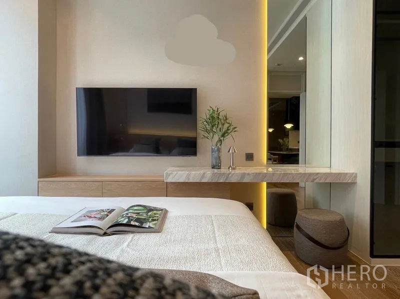 Condominium for rent or sale in Pathum Wan, Bangkok - Bedroom detail showing TV wall, marble floating vanity with mirror and soft LED strip lighting.