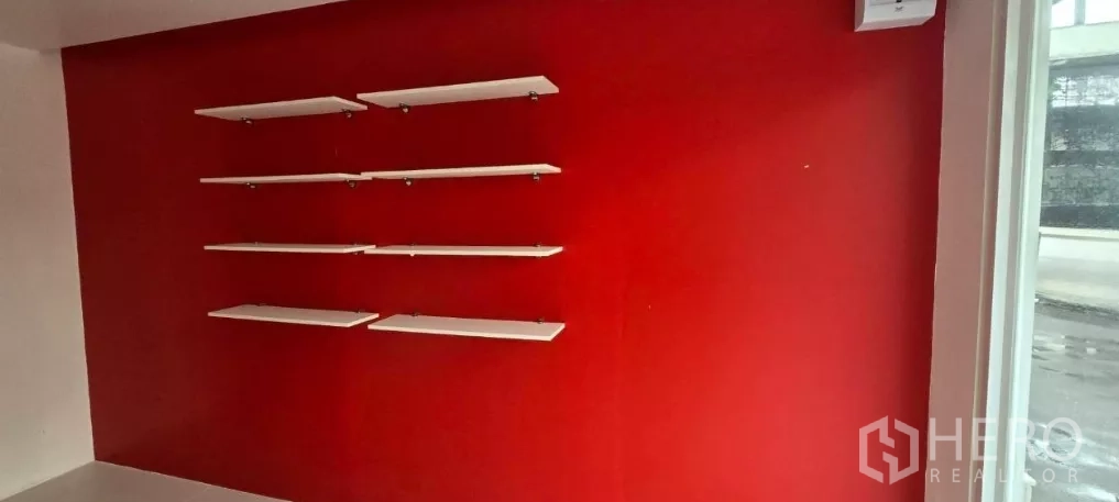Retail Space for rent in Watthana, Bangkok - Red feature wall fitted with multiple white floating display shelves near the shop window.