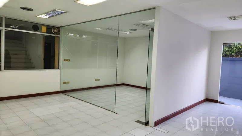 Office Space for rent or sale in Khlong Toei, Bangkok - Glass-partitioned office room with white tile flooring and neutral walls.