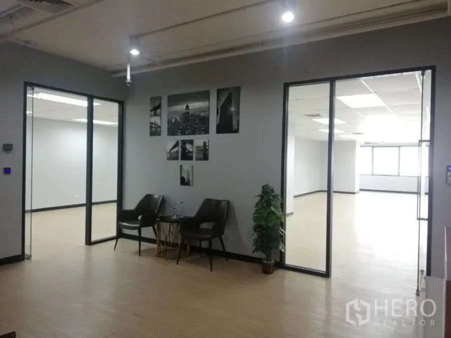 Office Space for rent in Watthana, Bangkok - Modern office reception with two lounge chairs, wall art, and glass-partitioned rooms.