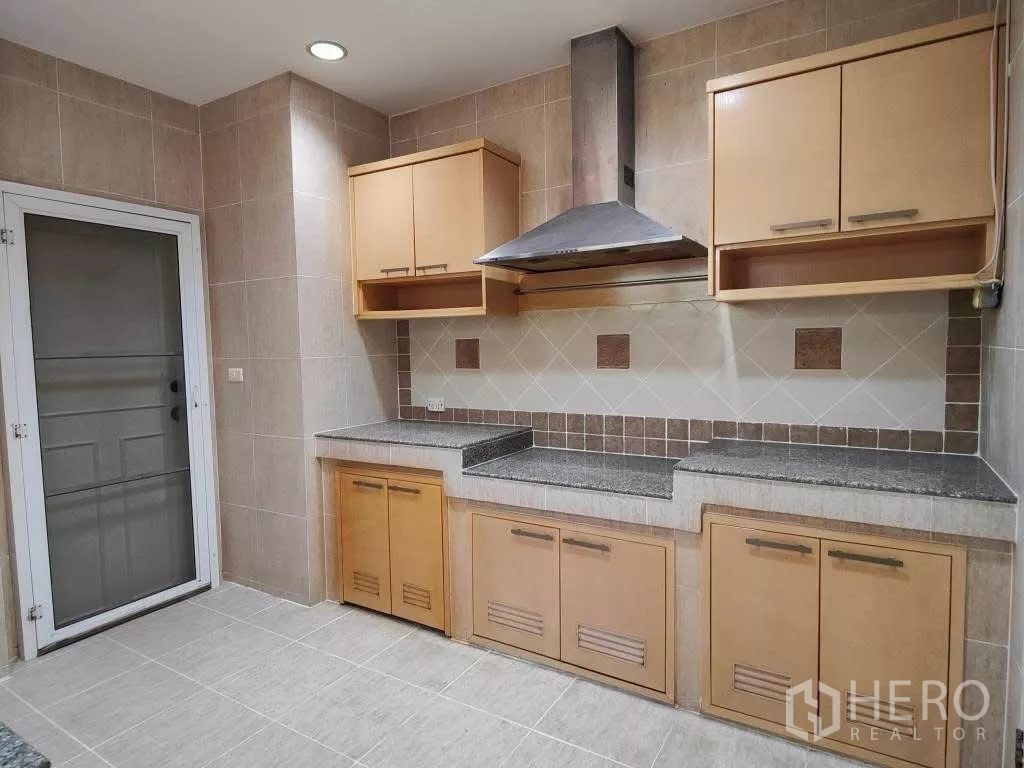 Detached House for rent or sale in Mueang Nonthaburi, Nonthaburi - Main kitchen with tiled walls, granite countertops, cabinets and range hood.