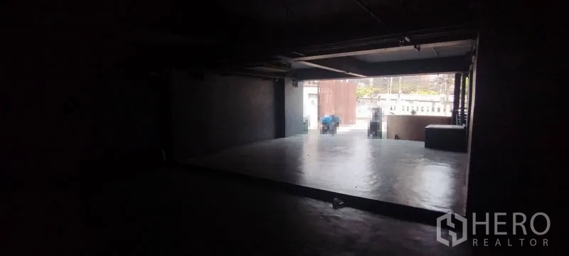 Office Space for rent in Chatuchak, Bangkok - Dim industrial workspace with a raised concrete platform opening to street frontage via roller shutter.