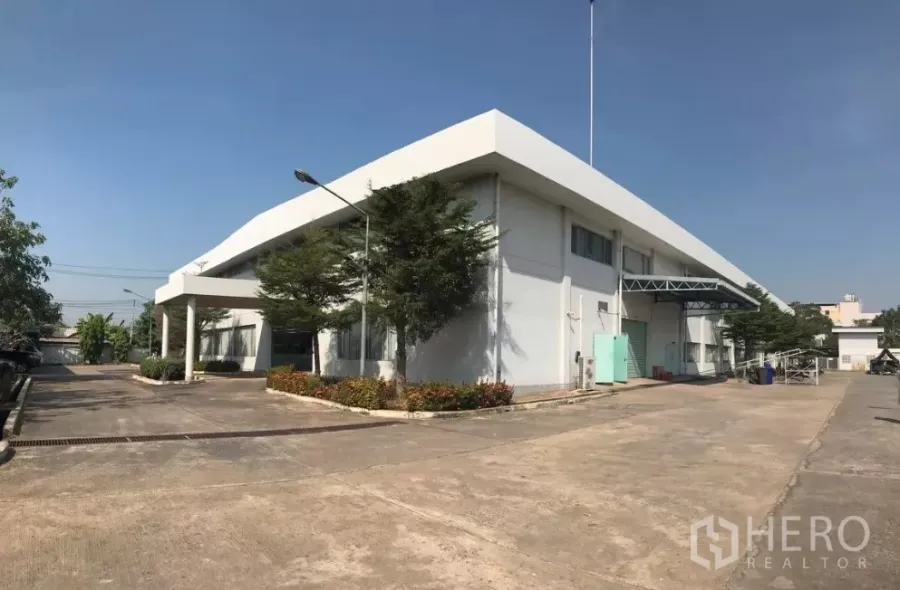 工厂 出售在Khlong Luang, Pathum Thani - Khlong Luang现代白色工厂外观，设装卸雨棚、宽阔车道与绿化。