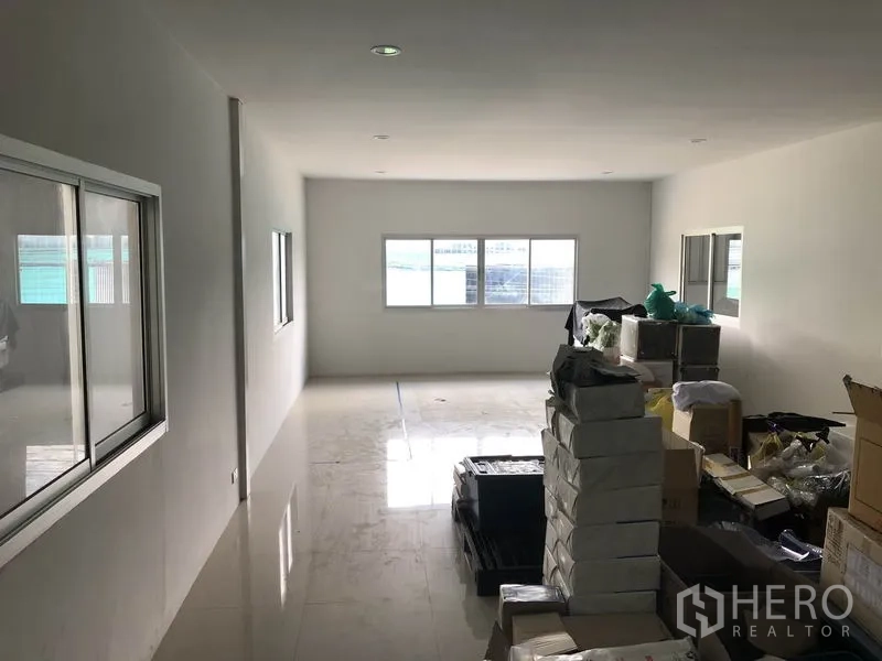 Warehouse for rent in Bang Kapi, Bangkok - Bright internal office area with windows on both sides and stacked boxes on polished flooring inside the warehouse.