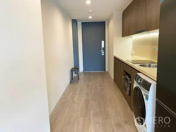 Condominium for rent in Pathum Wan, Bangkok - Galley kitchen corridor with built-in cabinets, cooktop, sink, oven, refrigerator and washing machine.