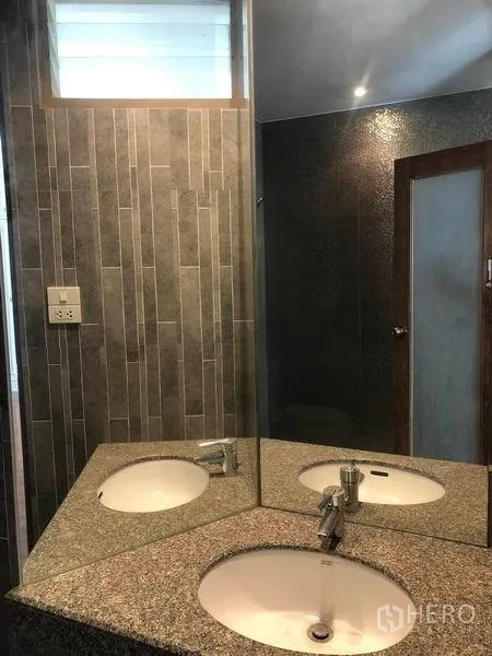 Detached House for rent in Watthana, Bangkok - Bathroom with granite countertop, large mirror and tiled walls.