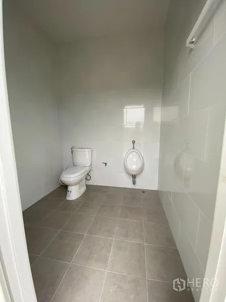 Warehouse for rent or sale in Bang Len, Nakhon Pathom - Clean tiled restroom with toilet and urinal in the facility.
