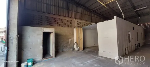 Warehouse for rent in Sathon, Bangkok - Entrance area of the warehouse with small storage room, industrial lighting and concrete flooring.