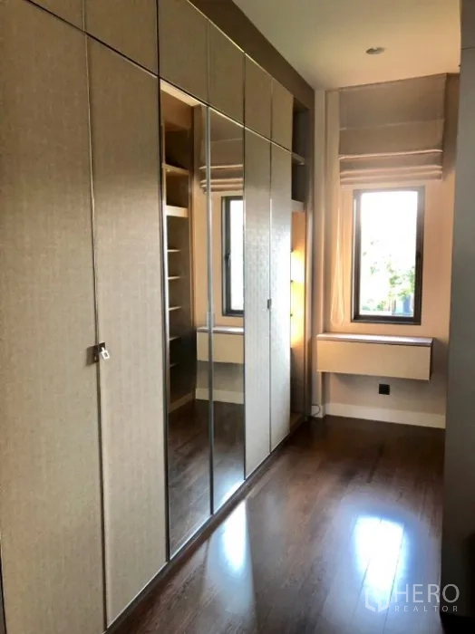 Detached House for rent in Bang Kapi, Bangkok - Walk-in closet with built-in wardrobes and mirrored doors beside a windowed vanity.