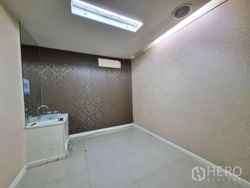 Shophouse for rent in Watthana, Bangkok - Interior room with sink cabinet, patterned walls and fluorescent ceiling light.