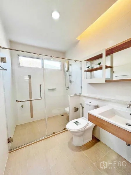 Detached House for rent in Prawet, Bangkok - Contemporary bathroom with wide glass shower, backlit ceiling and shelving.