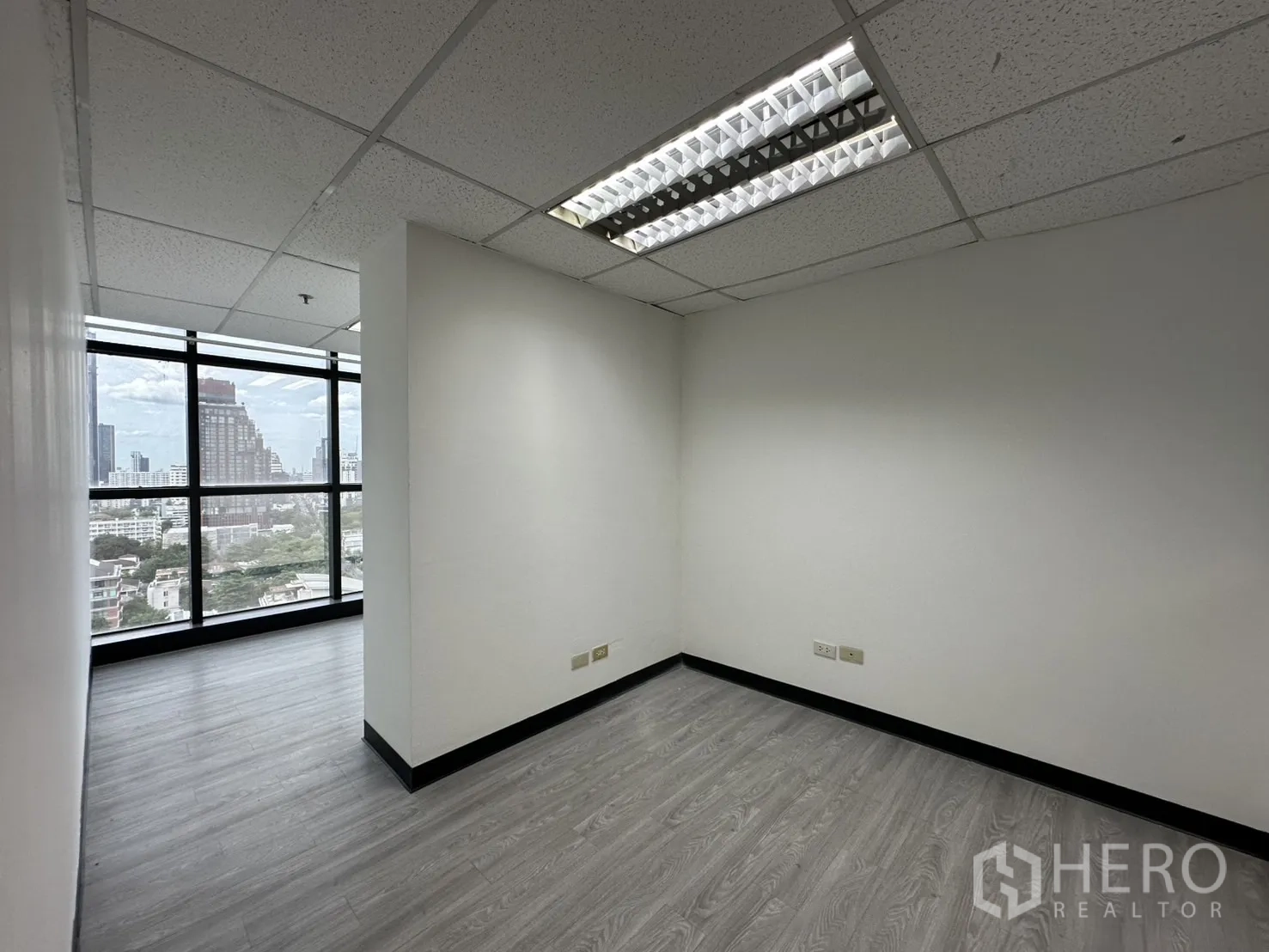 Office Space for rent in Watthana, Bangkok - Compact private office with large windows, neutral walls and fluorescent lighting overlooking Bangkok.