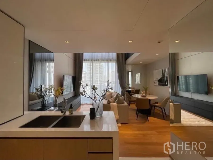Condominium for rent in Khlong Toei, Bangkok - Open-plan kitchen with island facing a bright living and dining area with floor-to-ceiling windows and city views.