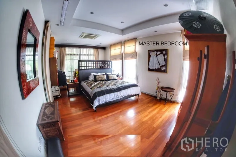 Detached House for rent in Watthana, Bangkok - Master bedroom with king bed, corner windows and polished wood flooring.