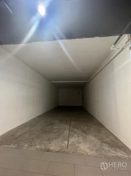 Retail Space for rent in Watthana, Bangkok - Long narrow shop interior in shell condition with a ceiling spotlight and white side walls.