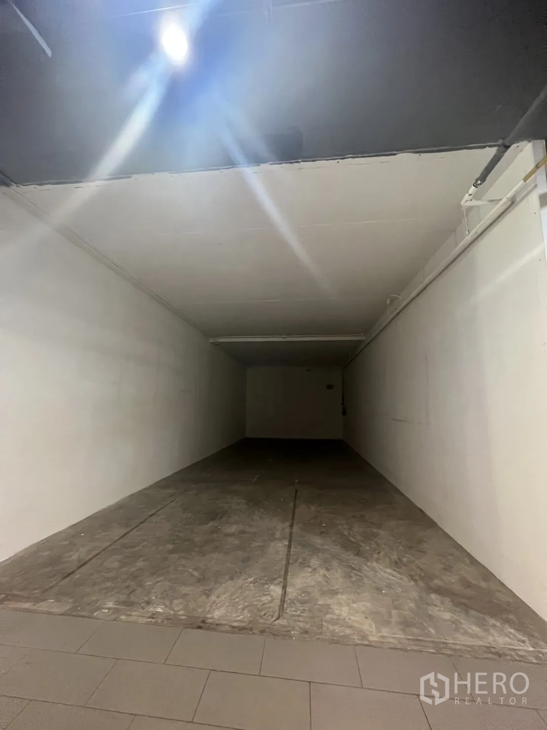 Retail Space for rent in Watthana, Bangkok - Long narrow shop interior in shell condition with a ceiling spotlight and white side walls.