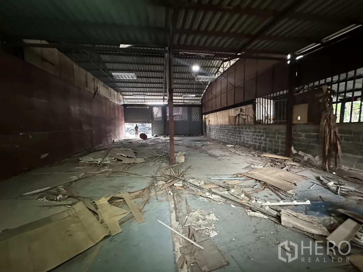 Warehouse for rent or sale in Yan Nawa, Bangkok - Long hall facing the shuttered entrance with exposed steel frame and ventilation blocks.