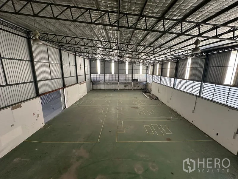 Warehouse for rent in Suan Luang, Bangkok - Aerial view of expansive high‑ceiling warehouse hall with insulated roof and marked floor.