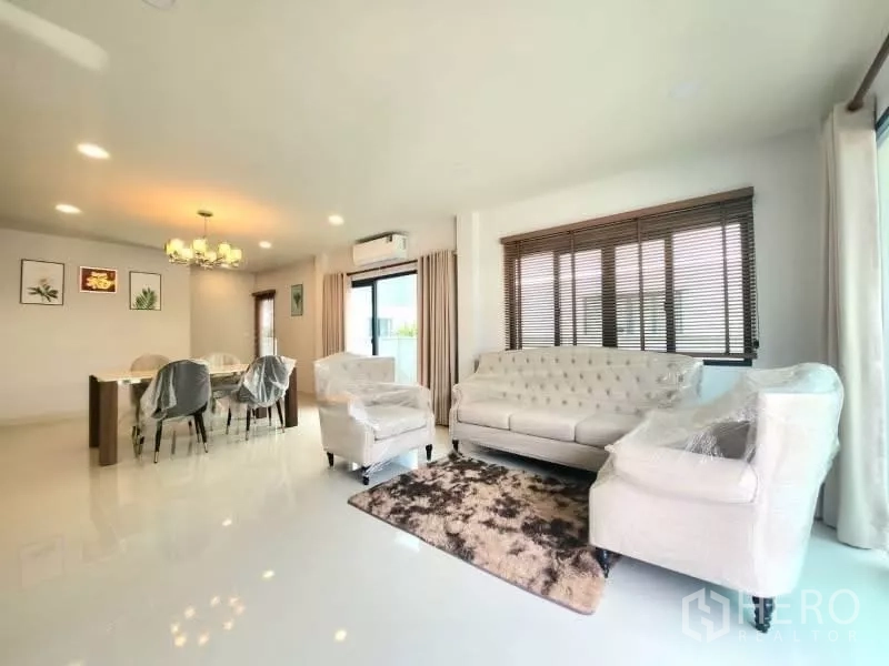 Detached House for rent in Bang Phli, Samut Prakan - Bright open-plan living room with light sofas, large windows and adjoining dining area.